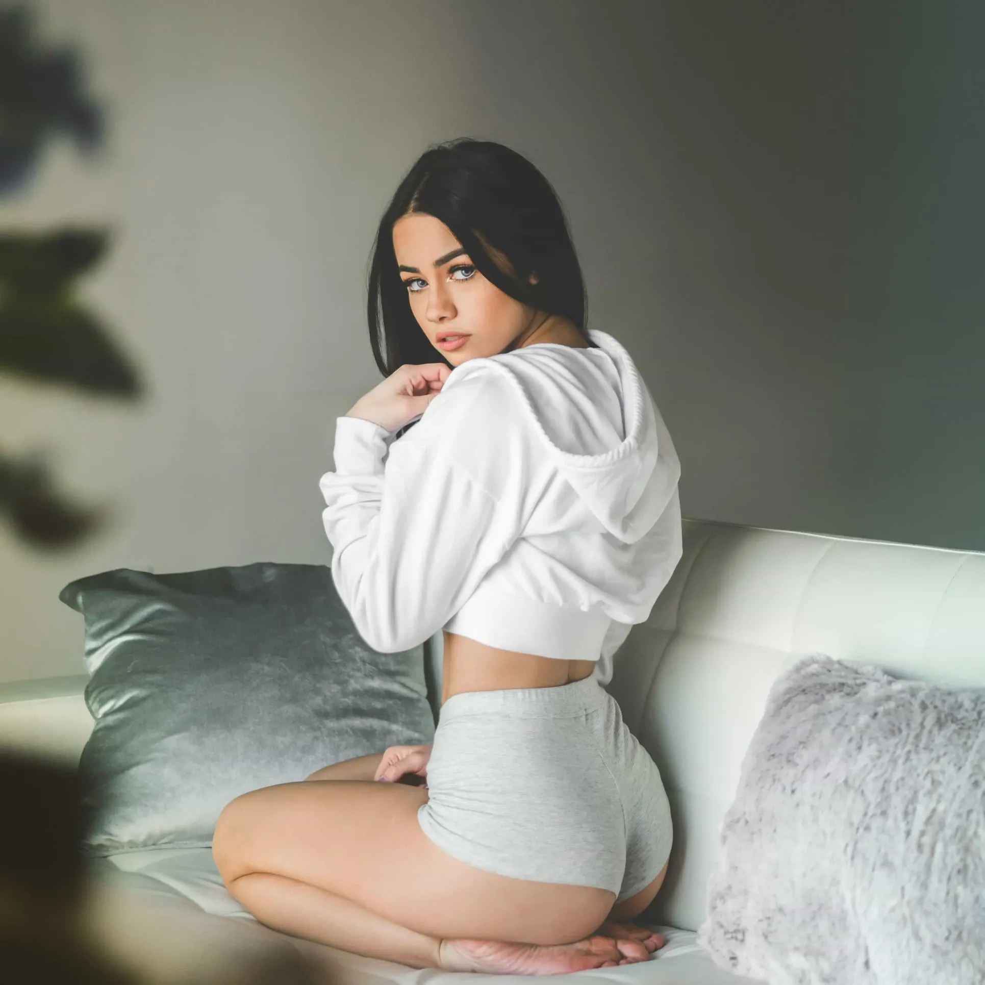 Young woman in grey used underwear and white hoodie on a sofa – intimate and sensual image representing used underwear for sale on DirtyPanties®